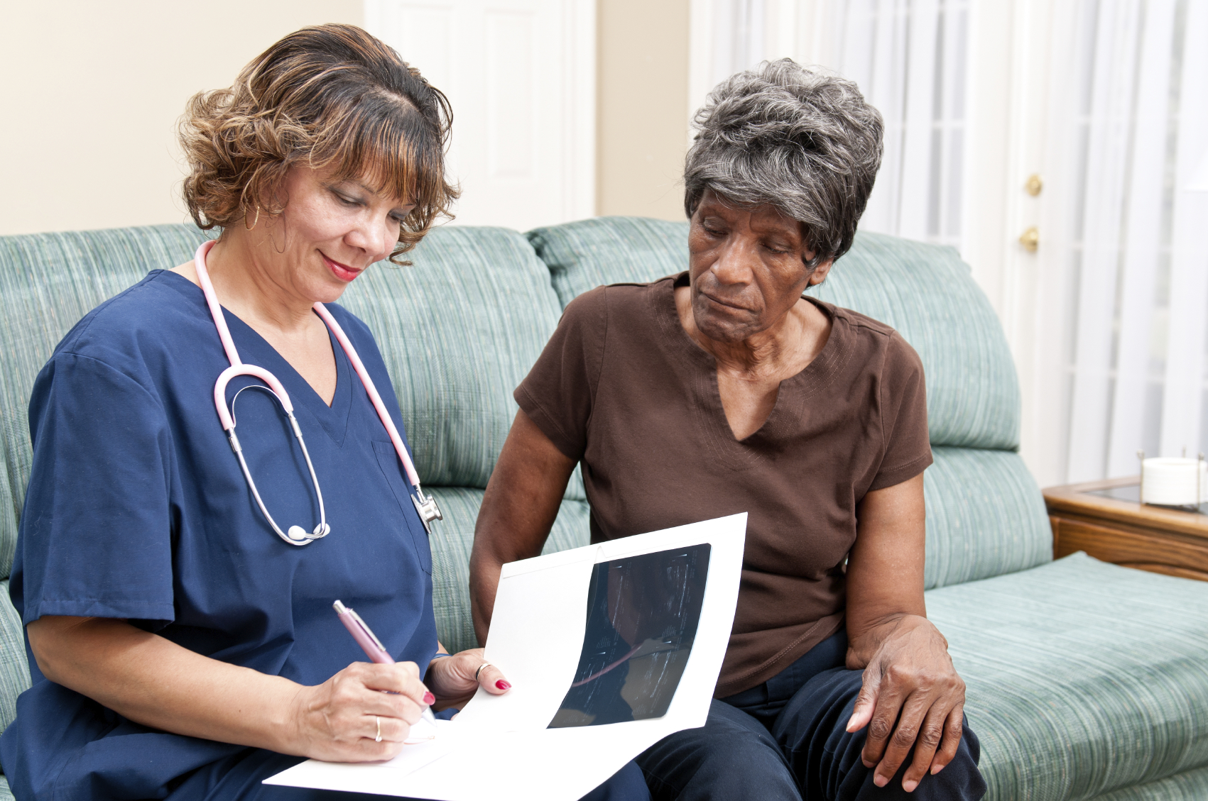 Professional African American Woman Heathcare Worker assisting an older African American woman in her home