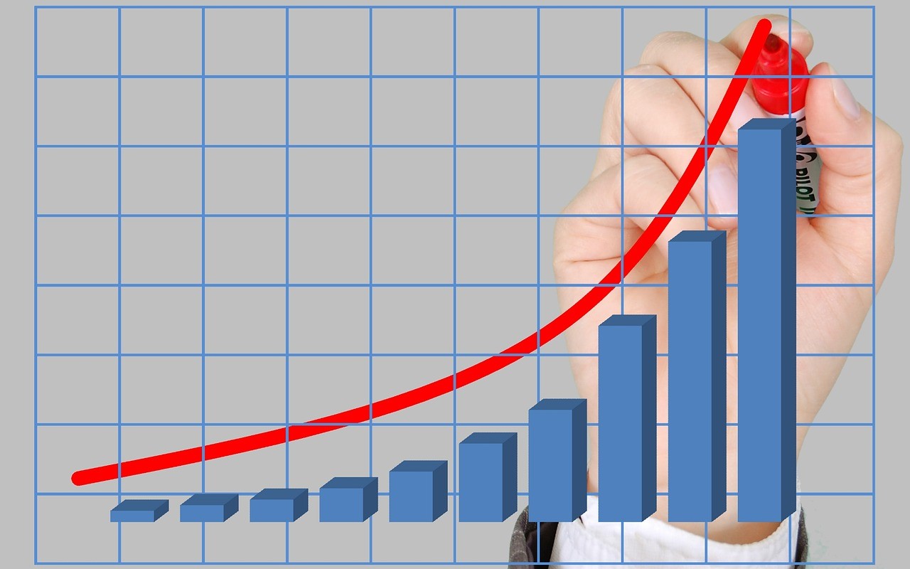 image of a bar graph with a hand superimposed drawing a red line of growth with a marker